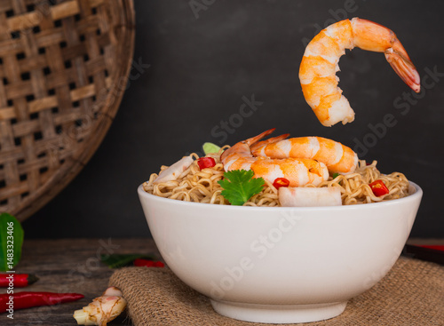 Front view of ramen instant noodle soup with shrimp in white bowl on wooden table background. Asia Food, Tom Yum Kung