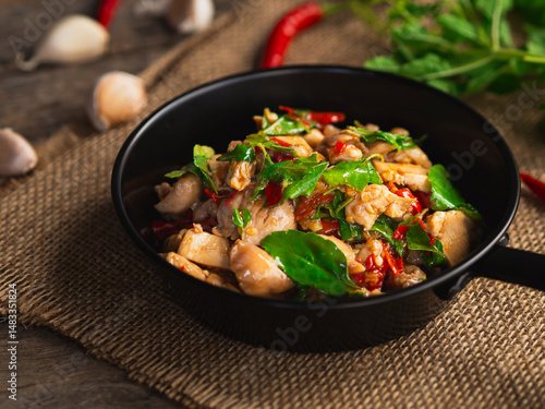 Stir fried chicken with basil and chili in mini pan on wooden background. Thai Food
