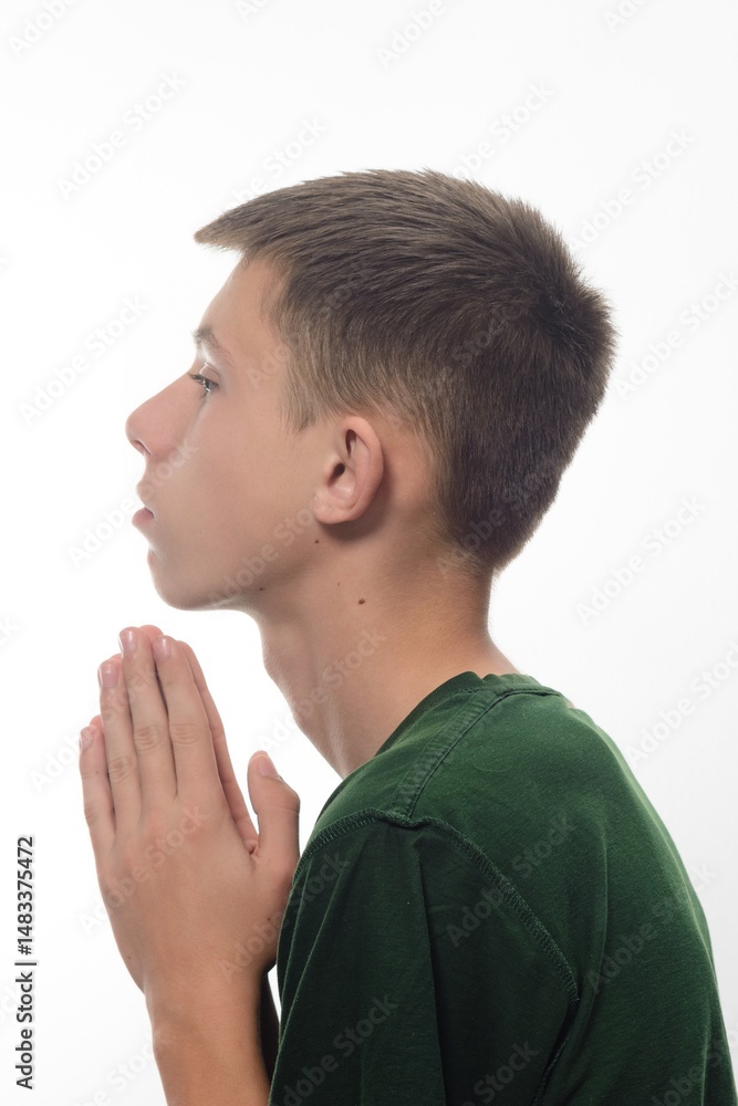 Fototapeta premium A teenage boy in a green T-shirt folded his hands in prayer.