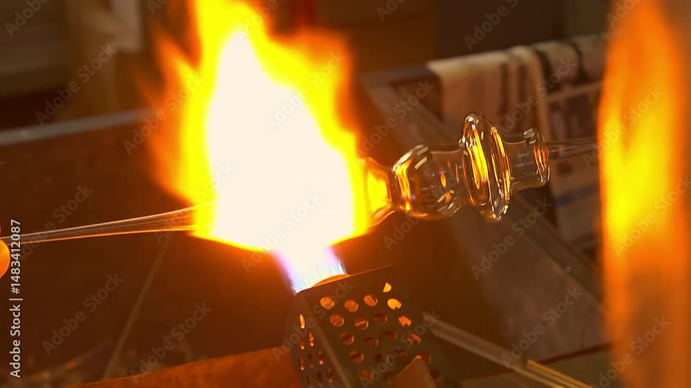 Detail of artisan glassblowing process using a torch to shape molten glass in Italian workshop