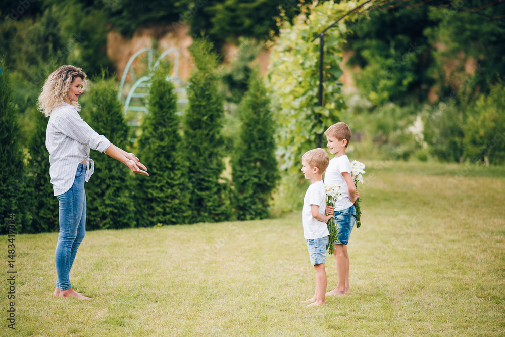 Fototapeta premium Two sons give their mother a bouquet of flowers. Mother's Day. Mom received a bouquet of flowers as a Mother's Day gift.