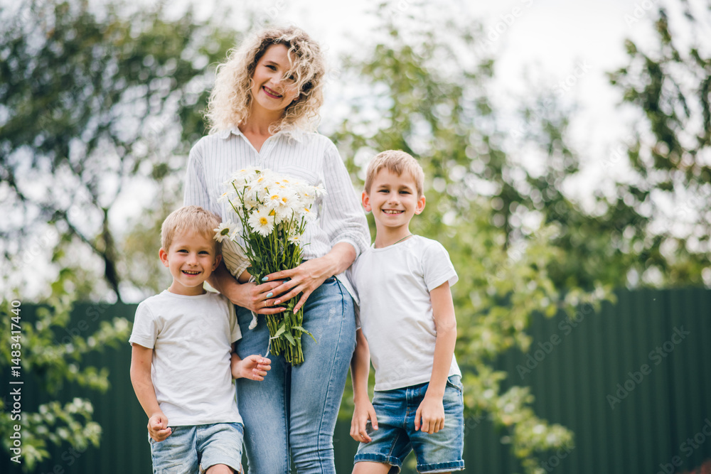 Fototapeta premium Two sons give their mother a bouquet of flowers. Mother's Day. Mom received a bouquet of flowers as a Mother's Day gift.