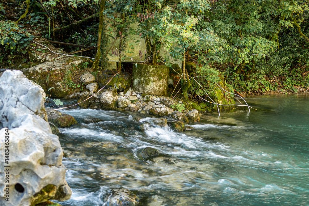 Obraz premium A river rapid of water flowing out of the crystal clear mountain lake Ritsa. The river Yupshara flows out of Lake Ritsa. 