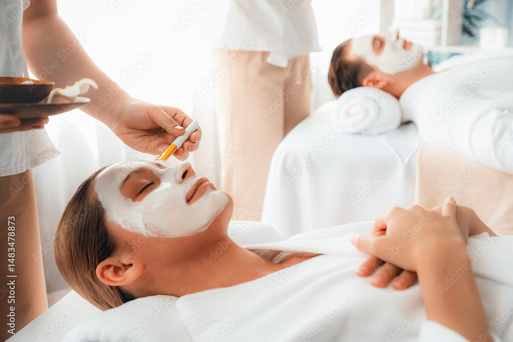Obraz premium Serene ambiance of spa salon, couple indulges in rejuvenating with luxurious face cream massage with modern daylight. Facial skin treatment and beauty care concept. Quiescent