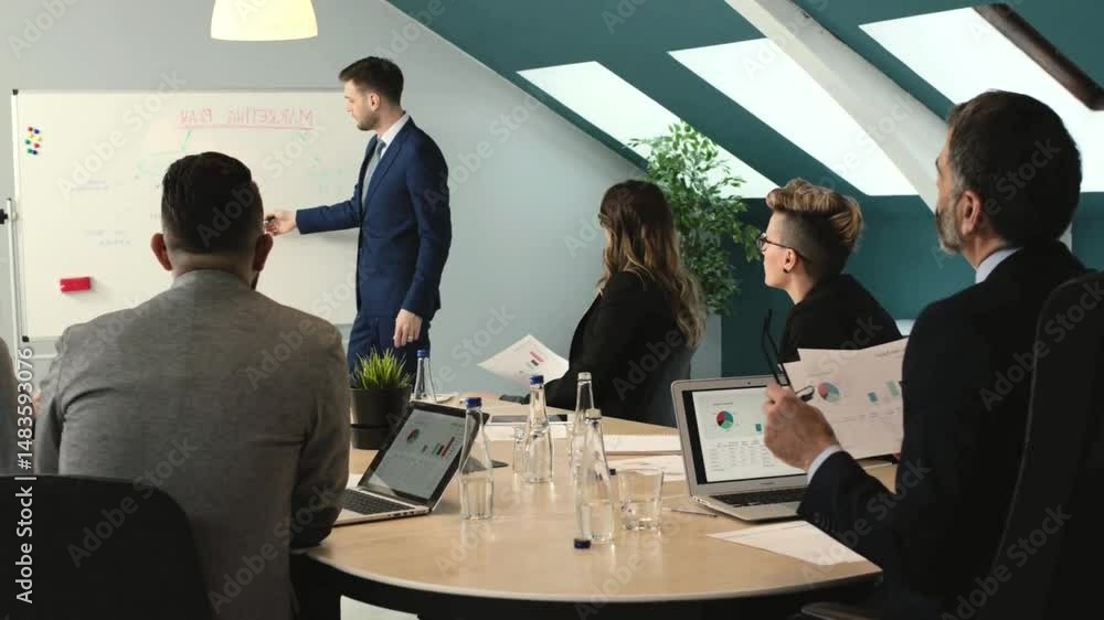 business team having a presentation in the office with a man pointing at a whiteboard business team having a presentation in the office with a man pointing at a whiteboard