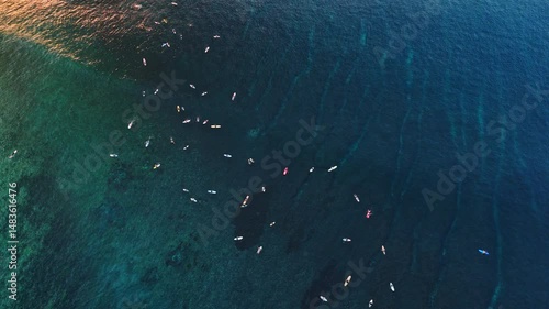 Aerial view of surf spot with blue ocean, waves and surfers. Sea with sunset light