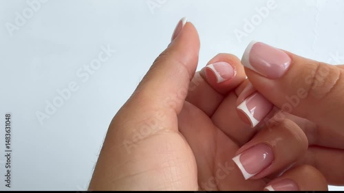 Moisturizing pink oil for cuticles. The woman cares for hands and nails, close up. Woman applying oil from pipette to cuticle on light background, macro. Healthy nails concept.