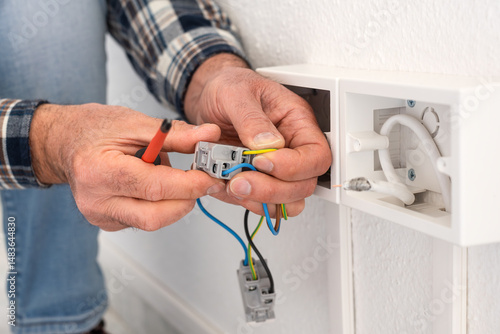 Electrician worker inserts electrical cables into the socket terminals of an electrical system. Construction industry.