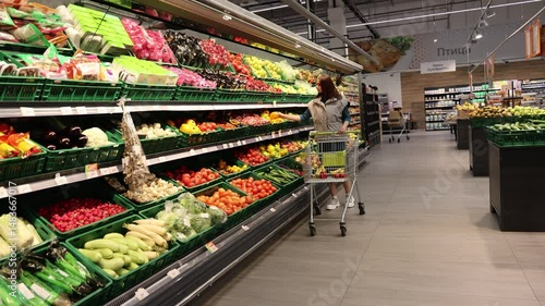Girl in the grocery store in the vegetable section. 4K Video