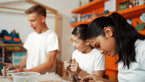 Caucasian boy modeling bowl of clay while cute asian girl working on dough at pottery workshop. Skilled highschool student playing on dough while wear muddy shirt at art lesson. Creative. Edification.