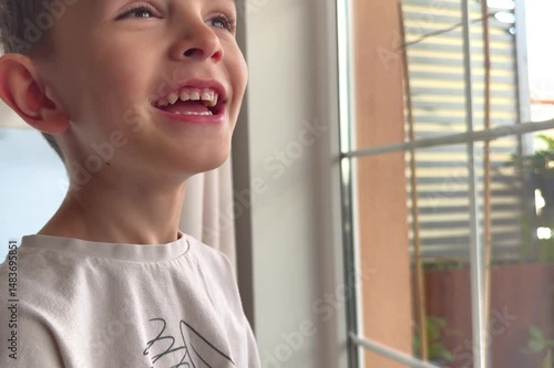 Close-up Portrait of Happy Little Child Bursting in Laugh. Kid Boy Laughs Indoors Closeup. Portrait of Little Boy Child Looking and Smiling to Camera. Face Funny Contemplative Kid. Slow Motion.