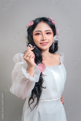 Charming Asian woman with a joyful smile and confident expression, wearing a white dress and floral hairpieces. Her face radiates happiness, elegance, and modern femininity.