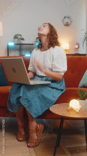 Tired young woman using laptop, suffering from headache problem tension and migraine, stress at home room. Girl works on netbook, sends messages, makes online purchases, watching movies. Vertical.
