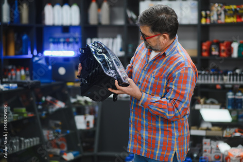 Tableau sur toile Mechanic choosing headlight in auto parts store