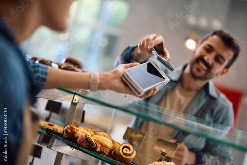 Photos Close up of bakery customer paying with smart phone.