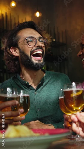 Vertical HD video of young group of diverse friends enjoying weekend together cheering with beers at brewery bar - International friendship concept