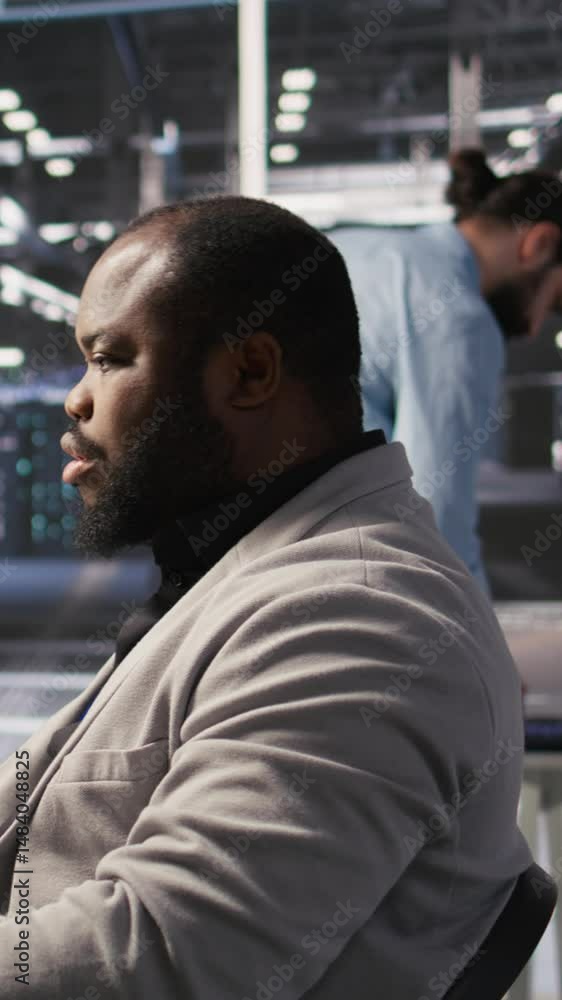 Vertical video Satisfied data center employee finishing system maintenance on supercomputers. Smiling technician pleased by successful AI model training results on PC while overseeing server Vertical video Satisfied data center employee finishing system maintenance on supercomputers. Smiling technician pleased by successful AI model training results on PC while overseeing server
