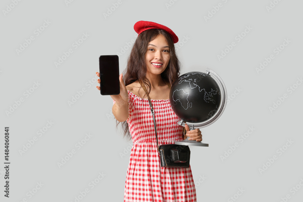 Obraz premium Young Asian woman with globe and mobile phone on white background. Travel concept
