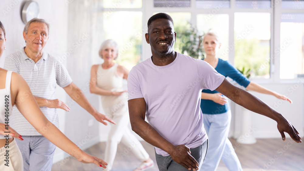 Obraz premium Active mature men and women practicing Hip-hop dance in training hall during dancing classes