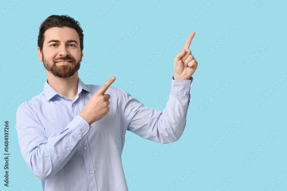 Young man pointing up on blue background Young man pointing up on blue background