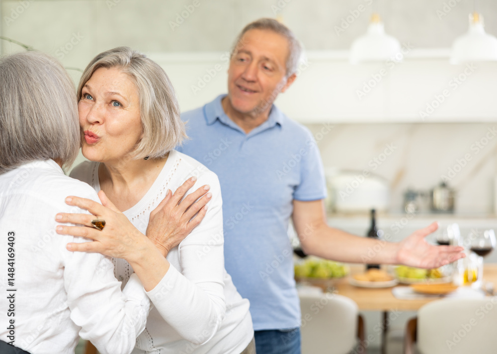 Fototapeta premium Two elderly women friends hugging when meeting in kitchen