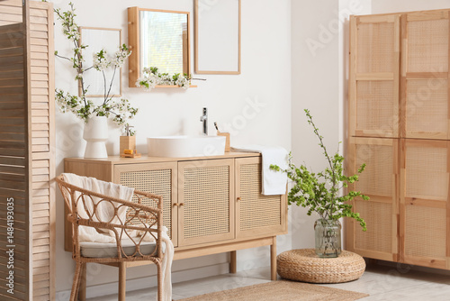 Interior of bathroom with sink, blossoming branches and armchair