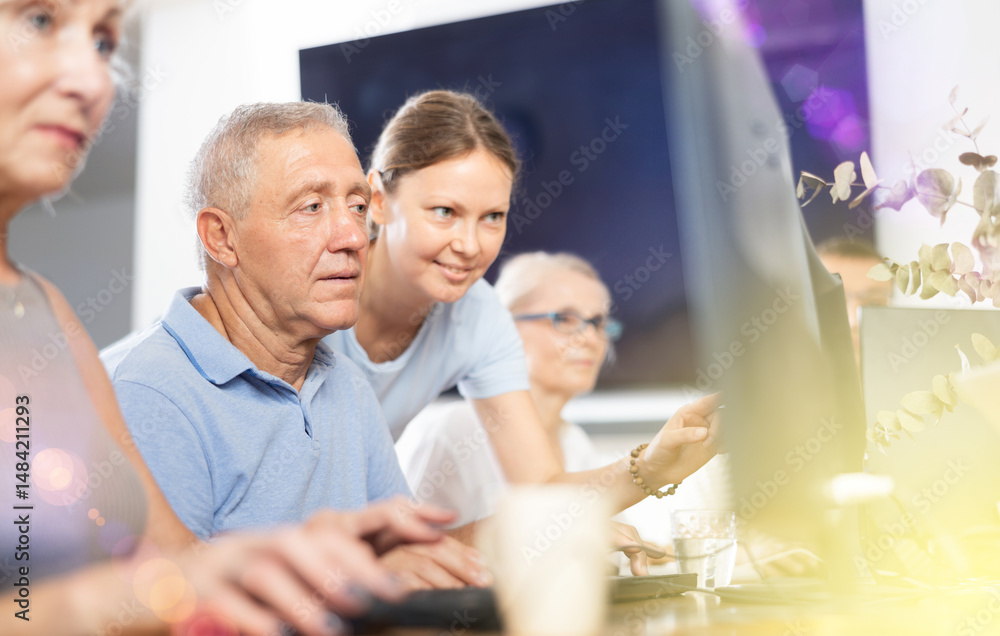 Curious mature man engaged in IT training with help of teacher in computer courses Curious mature man engaged in IT training with help of teacher in computer courses