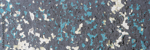 Peeling paint on the wall. Panorama of a concrete wall with old cracked flaking paint. Weathered rough painted surface with patterns of cracks and peeling. Wide panoramic texture for design background