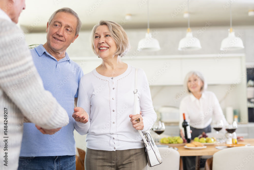 Fototapeta premium Couple of elderly women and men meeting friends in kitchen at home