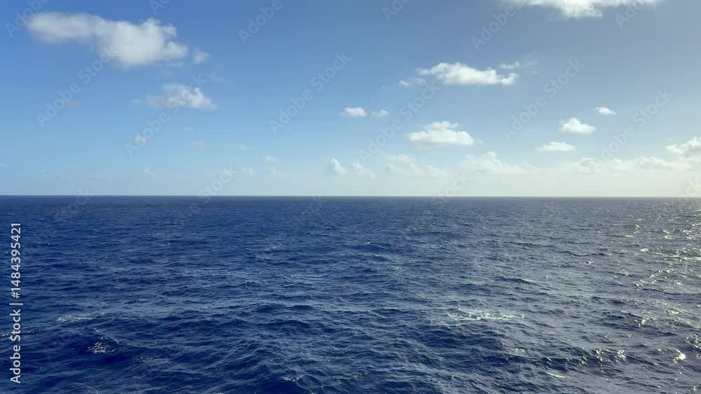 Vast blue ocean under a clear sky with scattered clouds Vast blue ocean under a clear sky with scattered clouds