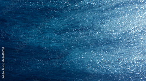 Abstract blue paint background wavy fluid texture with white splatter like snow, winter concept.