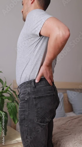 A man gets out of bed and experiences acute lower back pain, stretches and massages the sore muscles conditions include sciatica, hernia, arthritis Concept Wellness Center, Physical Therapy Clinic.