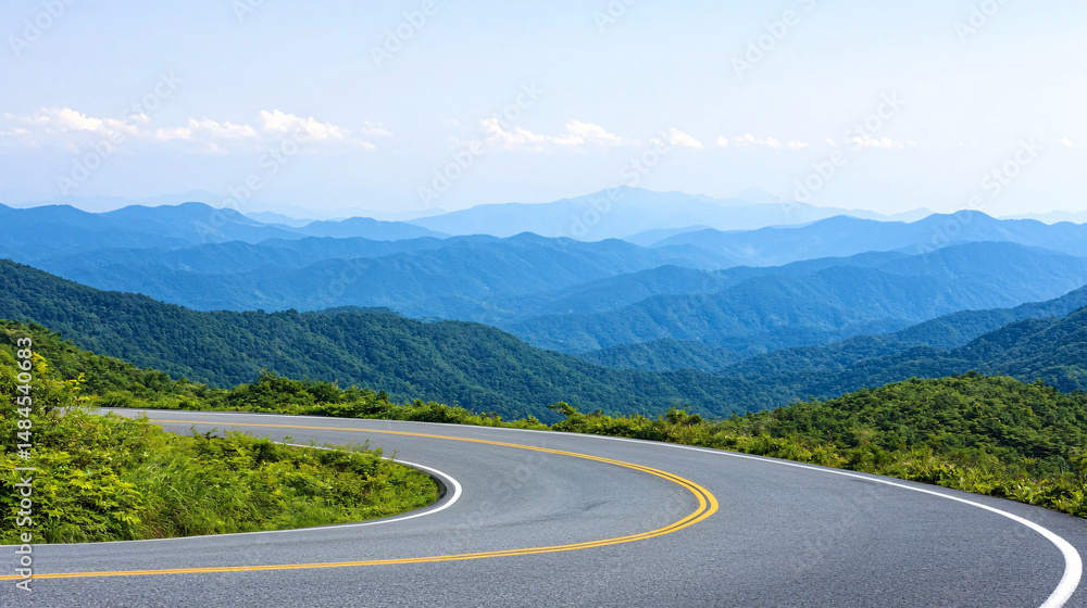 Naklejka premium A winding road cuts through lush green mountains under a clear blue sky on a bright summer day.