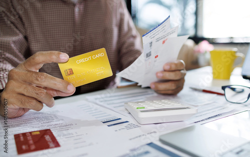 asian man calculate monthly expenses from receipt and many bill of various expenses after spending via credit card and must be pay back soon