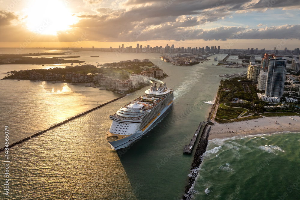 Fototapeta premium Big passenger cruise liner ship departing at main channel in Miami harbor near South Beach high luxurious hotels and apartment buildings