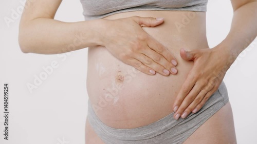 Wallpaper Mural Frontal shot of a woman massaging lotion into her pregnant belly using gentle circular and pinching motions. Torontodigital.ca