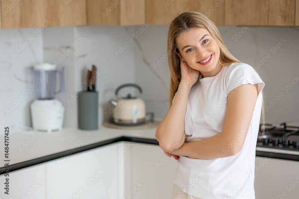Smiling woman standing in modern kitchen with appliances and natural decor Smiling woman standing in modern kitchen with appliances and natural decor