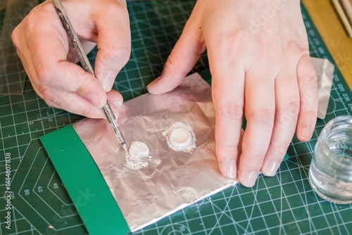 Close-up of hands working with silver clay with a fine brush, showcasing precision and detail.