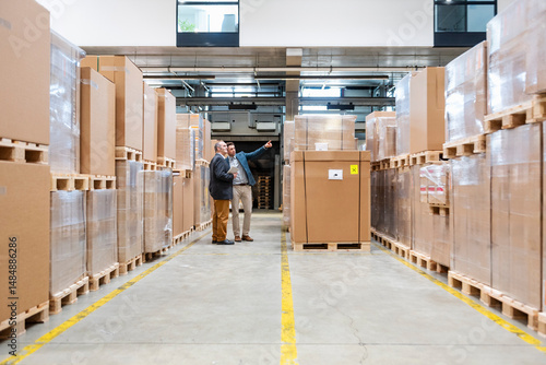Two employees having a meeting in a warehouse surrounded by cardboard boxes