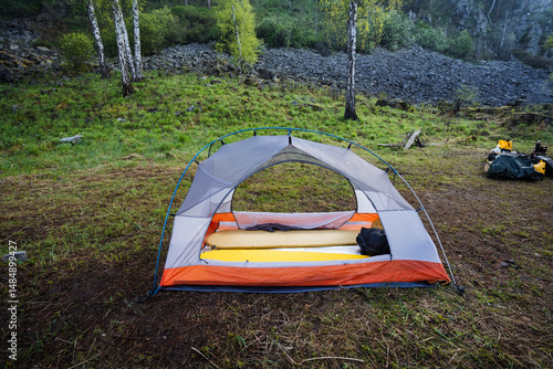 A serene camping scene beautifully showcases a cozy tent setup nestled within a lush green forest, embodying both adventure and tranquility, inviting everyone to explore the wonders of nature photo