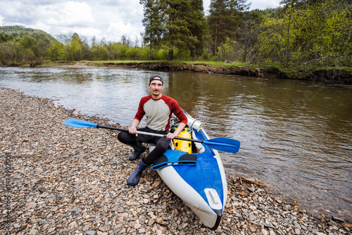 An adventurous kayaker takes some welldeserved time to relax by the beautiful riverbank, enjoying the serene natural setting that surrounds them in this delightful outdoor environment