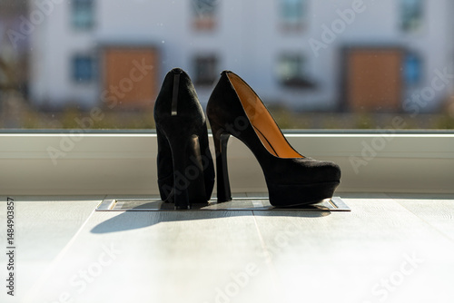 Black ladies pumps on the floor in front of a window