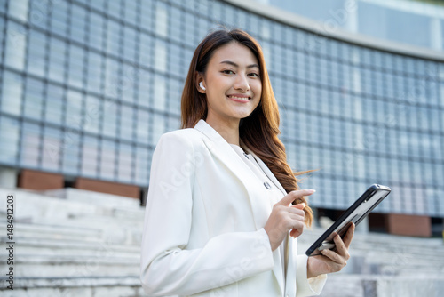 Portrait beautiful Businesswoman in suit with tablet standing at the buildings downtown. Confident woman using tablet. Executive Smart businessman