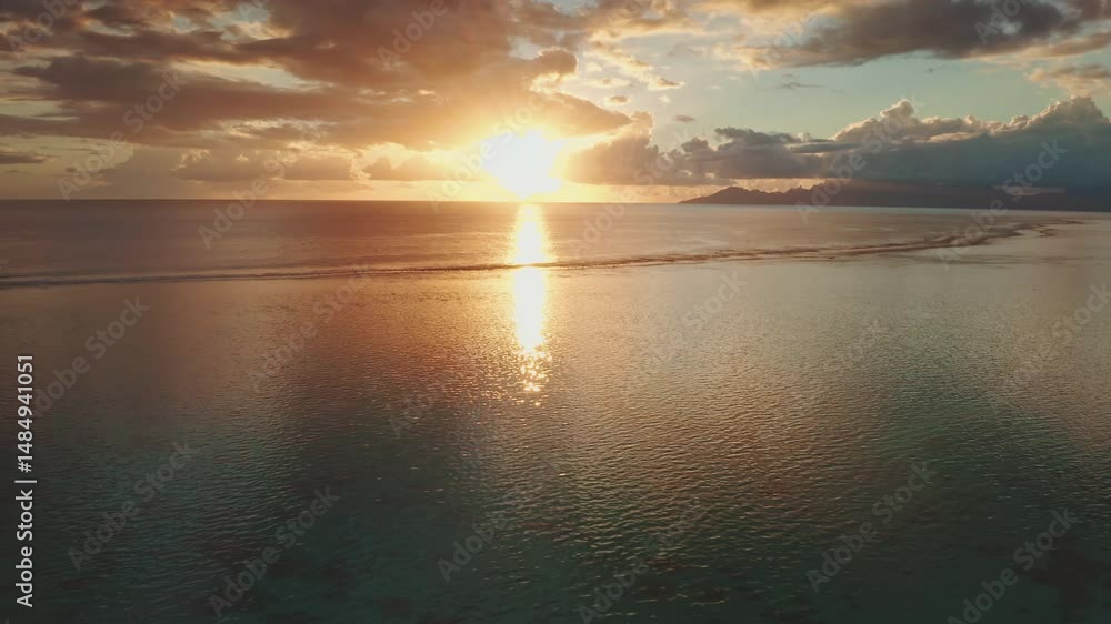 Golden hour sunlight reflects on the calm ocean surface, creating a mesmerizing spectacle near a tropical island in Tahiti, with clouds adding depth to the picturesque scene Golden hour sunlight reflects on the calm ocean surface, creating a mesmerizing spectacle near a tropical island in Tahiti, with clouds adding depth to the picturesque scene