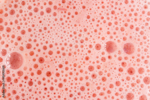 Pink foam texture with small bubbles on a light pink background. Close up macro view of liquid surface with air bubbles. Smooth beverage background abstract concept.