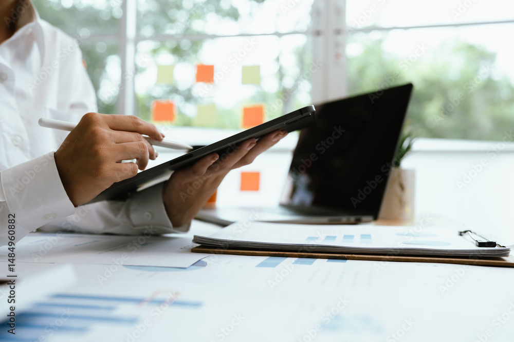 Obraz premium Close up of professional businessman sitting at desk in modern office, analyzing charts and financial documents, planning business growth and investment strategy.