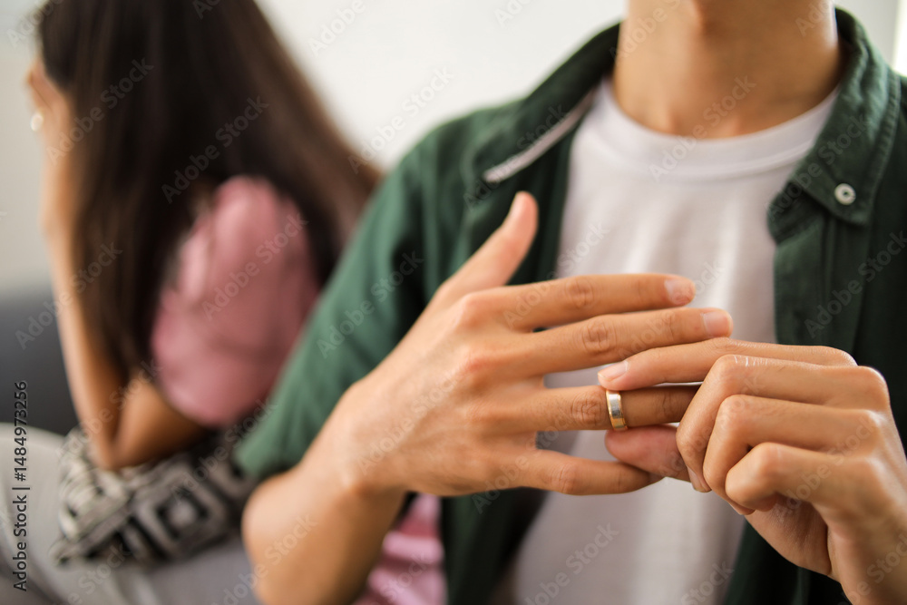 Fototapeta premium Relationship on the verge of collapse as husband removes ring in hand beside unhappy partner.