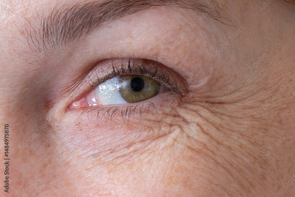 Obraz premium Cropped eye with wrinkles of middle aged caucasian woman smiling and looking at camera