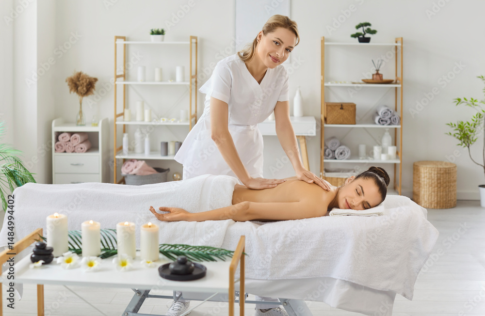 Horizontal view of relaxed woman enjoying aromatherapy and massage posing on couch with burning candles near, attending modern spa getting body procedures. Female therapist using acupressure technique Horizontal view of relaxed woman enjoying aromatherapy and massage posing on couch with burning candles near, attending modern spa getting body procedures. Female therapist using acupressure technique