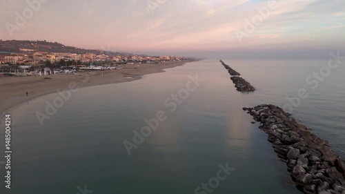 Aerial drone video of the Adriatic Sea at sunrise off Porto Potenza, Italy. Peaceful flyby capturing calm waters, golden reflections, and serene coastal beauty.